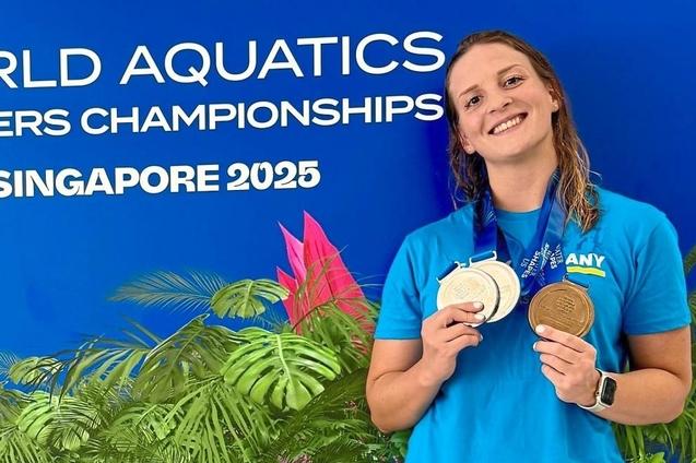 Sportlerin mit Medaillen vor einem blauen Hintergrund der Weltmeisterschaften im Wassersport, Singapur 2025.