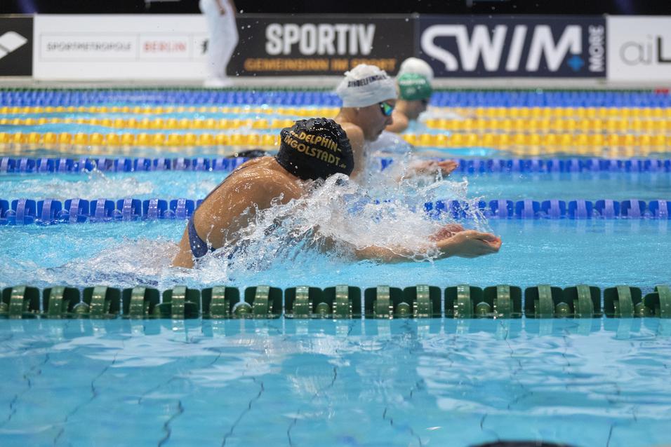 Schwimmer in einem Wettkampf schwimmen im Wasser, während Spritzer auf der Oberfläche entstehen.