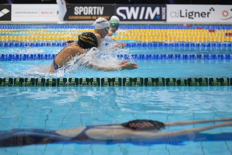 Schwimmer in einem Wettkampf schwimmen im Wasser, während Spritzer auf der Oberfläche entstehen.