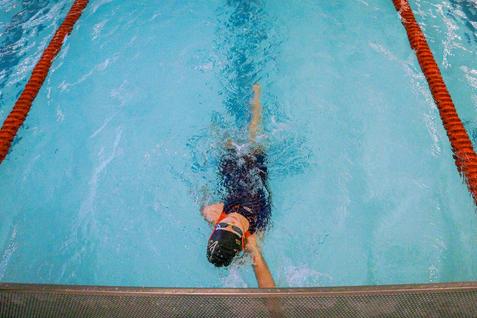 Schwimmer taucht in einem Hallenbad, während er sich mit einer armbewegenden Technik vorwärts bewegt.