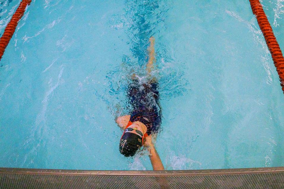 Schwimmer taucht in einem Hallenbad, während er sich mit einer armbewegenden Technik vorwärts bewegt.